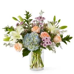 Bouquet of lilies, roses, and hydrangea in a clear glass vase