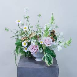 Pastel floral arrangement with pink roses and white daisies in a white vase