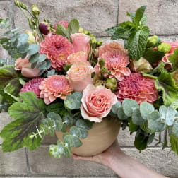 Pink roses and dahlias in a round vase with eucalyptus