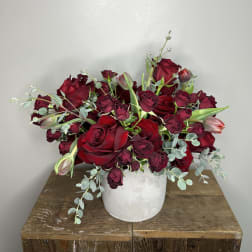Red and burgundy roses arranged in a white vase.