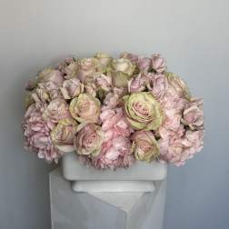 Pink roses and carnations arranged in a white rectangular vase