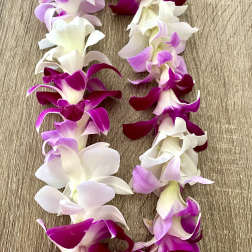 Garland of purple, pink, and white orchid blossoms on a wood surface