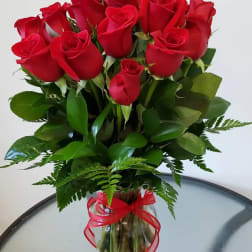 Bouquet of red roses in a clear glass vase with a red ribbon