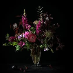Tall magenta and purple floral arrangement in a clear vase