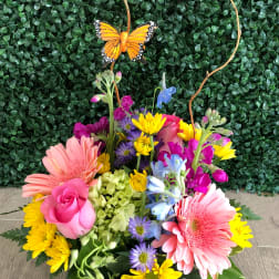 Colorful mixed bouquet in a white vase with a butterfly pick