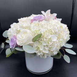 White hydrangea and roses in a white vase with pale purple accents