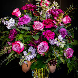 Large bouquet of pink and purple flowers in a clear glass vase