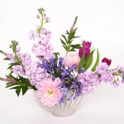 Pink and purple flowers arranged in a white vase