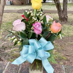 Bouquet of multicolored roses in a glass vase with a blue ribbon