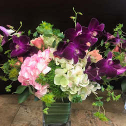 Purple orchids and pink hydrangeas in a square glass vase