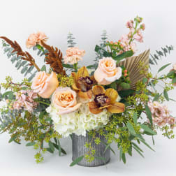 Peach roses and orchids in a ribbed metal vase