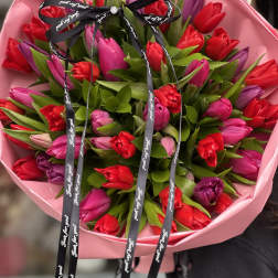 Bouquet of red and pink tulips wrapped in pink paper with a black ribbon