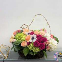 Mixed bouquet of roses, hydrangeas, and white blooms in a low basket