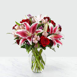 Bouquet of pink lilies and red roses in a clear glass vase