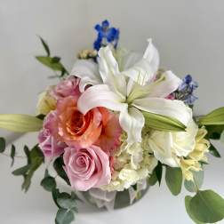 Bouquet of pink and white roses with a white lily in a glass vase