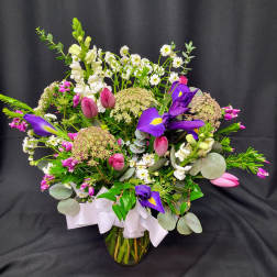 Mixed bouquet with purple irises, pink tulips, and white snapdragons in a glass vase