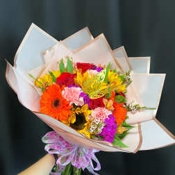 Colorful bouquet with roses, gerbera daisies, and carnations wrapped in pale paper