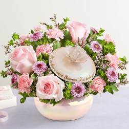 Pink roses and small purple flowers arranged in a round box with a lid.