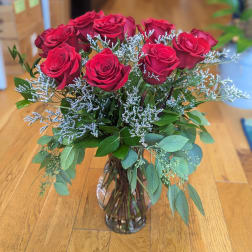 Red roses arranged in a clear glass vase with airy filler and greenery