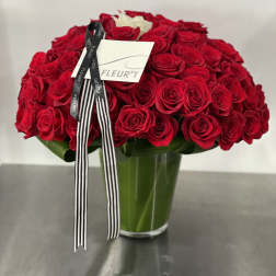 Large bouquet of red roses in a glass vase with a black-and-white ribbon