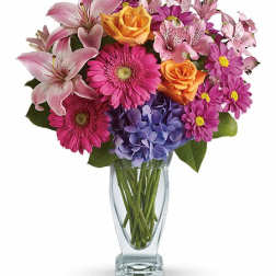 Mixed bouquet of lilies, roses, gerbera daisies, hydrangea, and daisies in a glass vase