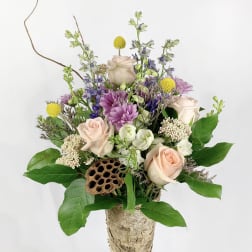 Mixed bouquet in a birch bark vase with pale roses and purple flowers