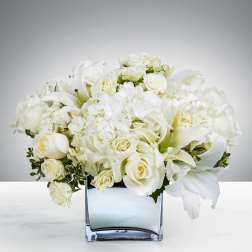 White roses and lilies arranged in a square glass vase