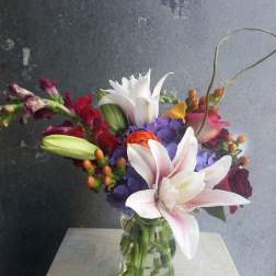 Mixed bouquet with lilies, hydrangeas, roses, and snapdragons in a glass vase