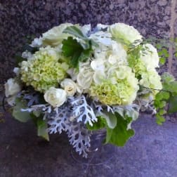 White and pale green floral arrangement in a clear vase