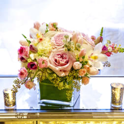 Pink and white floral arrangement in a square glass vase