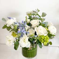 White roses and blue flowers in a green glass vase
