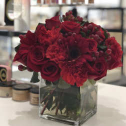 Red rose and carnation bouquet in a clear square vase