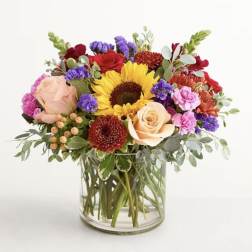 Mixed bouquet with a sunflower and roses in a clear glass vase