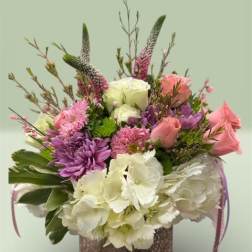 Mixed bouquet of pink, purple, and white flowers in a textured vase