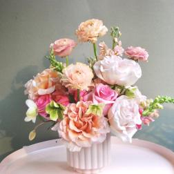 Pink and peach roses arranged in a white vase