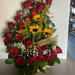 Basket arrangement of red roses with yellow sunflowers, baby's breath, and a gold ribbon