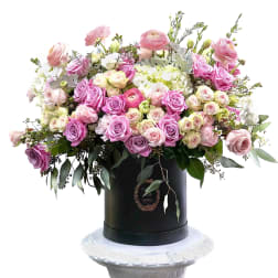 Large pink and white rose arrangement in a black hatbox