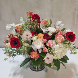 Mixed bouquet of red, pink, and white flowers in a glass vase