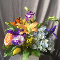 Mixed bouquet with lilies, roses, hydrangea, and a butterfly accent in a wooden box