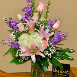 Pink lilies and roses with purple stock in a glass vase