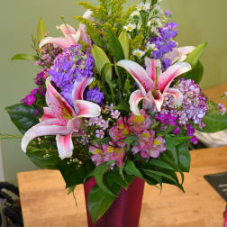 Pink lilies and purple flowers in a tall magenta vase