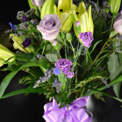 Bouquet of lavender roses and yellow lilies with a purple ribbon