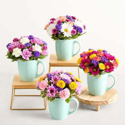 Four mixed flower arrangements in mint mugs on small stands