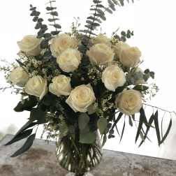 Cream rose bouquet in a clear glass vase with eucalyptus