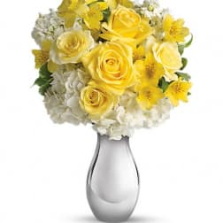 Yellow roses and white flowers arranged in a silver vase