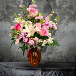Pink and white mixed flower arrangement in an amber glass vase