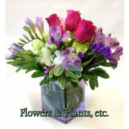Bouquet of pink and purple flowers in a square glass vase