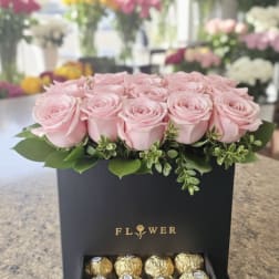Pink roses in a black gift box with chocolates in a drawer below