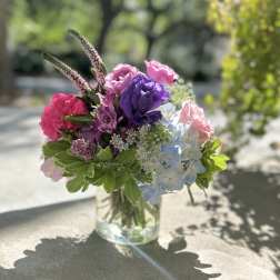 Colorful bouquet in a clear glass vase with pink, purple, and blue blooms