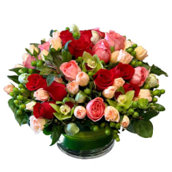 Mixed roses and orchids in a green glass vase